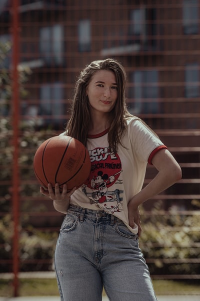 Wearing a white collar T-shirt woman carrying a basketball
